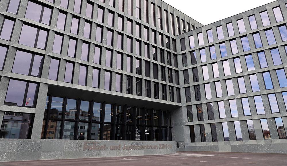 Modern gray stone building facade with grid of reflective windows