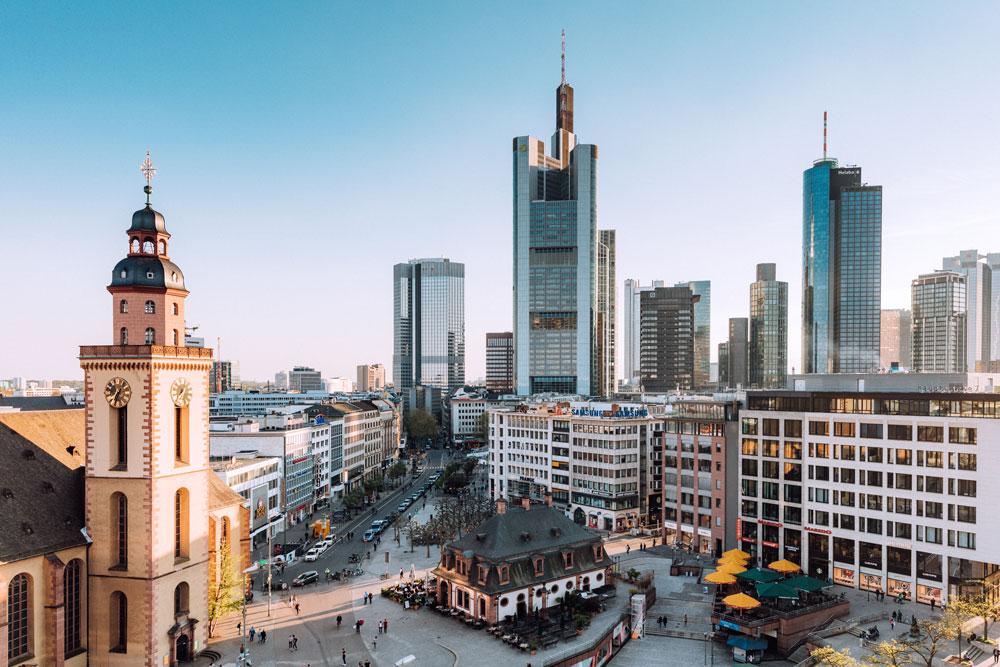 View of Frankfurt skyline featuring a historic church tower beside modern skyscrapers over a city plaza