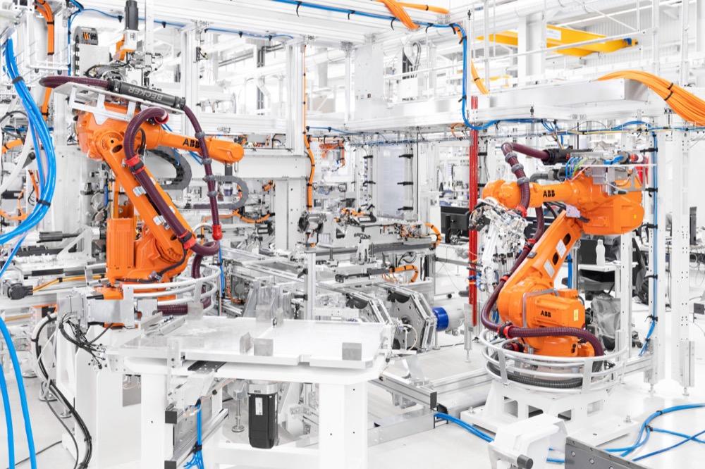 Orange ABB robotic arms on white automated assembly line with cables