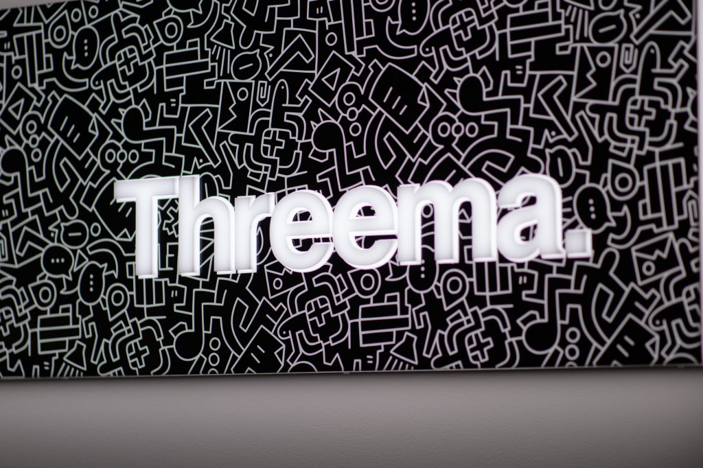 Cartel rectangular con "Threema" en blanco sobre fondo negro con líneas abstractas.
