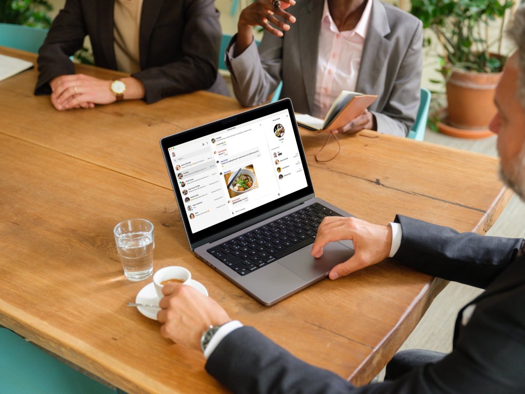 Geschäftsmann, der während eines Geschäftstreffens an einem MacBook arbeitet.