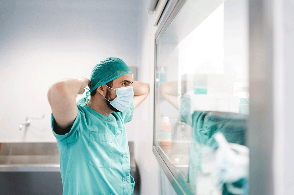 Medical professional looking through a window at the operating room.