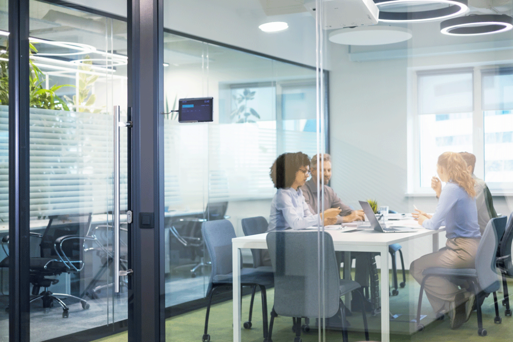 Vier Personen arbeiten und kommunizieren über Telefone und Laptops in einem Büro.