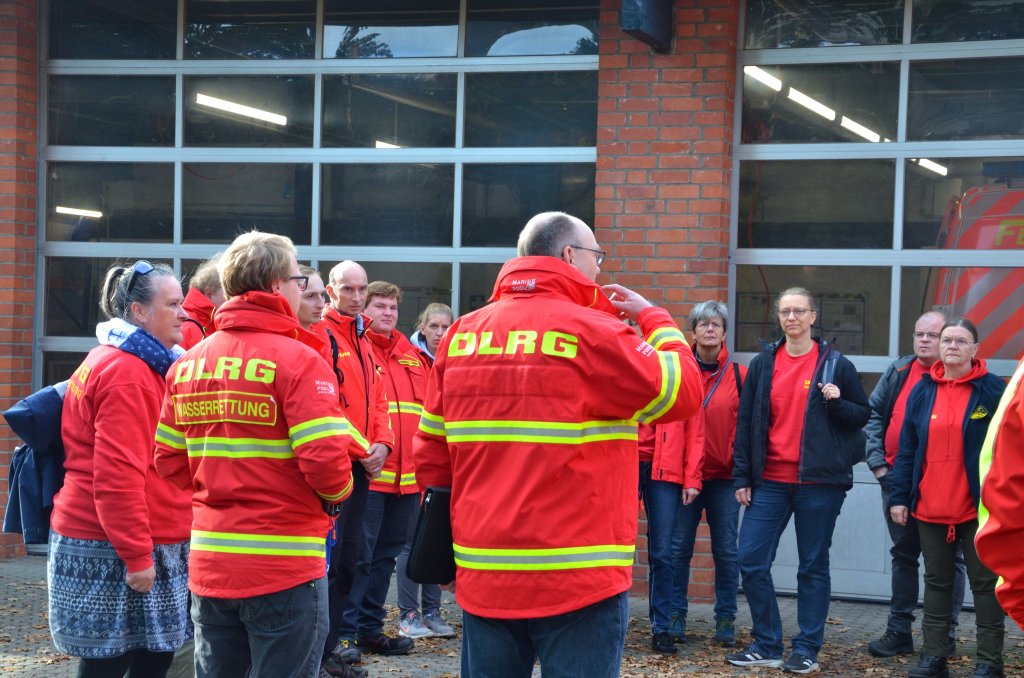 Mitglieder der DLRG Bargteheide bei der Einsatzbesprechung vor einem Hoftor.