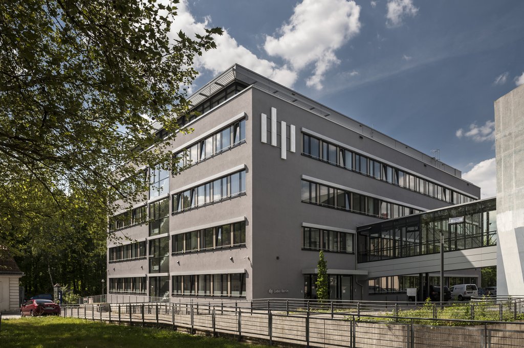 Modernes viergeschossiges Geb&auml;ude mit grauer Fassade, Schriftzug Labor Berlin und Glasvordach.