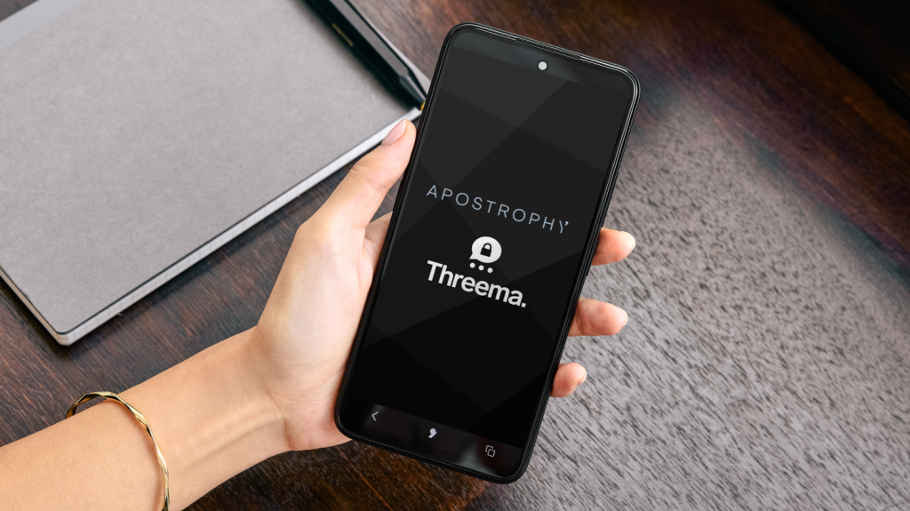 Hand holds smartphone displaying Apostrophy&rsquo; branded Threema secure messaging app screen.