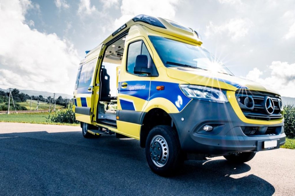 Furg&oacute;n ambulancia Mercedes Sprinter amarillo y azul con puerta lateral abierta mostrando equipo m&eacute;dico.
